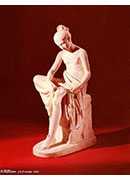 a carved white marble figure of a seated maiden